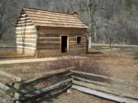 Small, rustic, log cabin with one door and one window on the front.