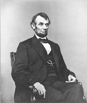 Man wearing suit and vest seated in chair