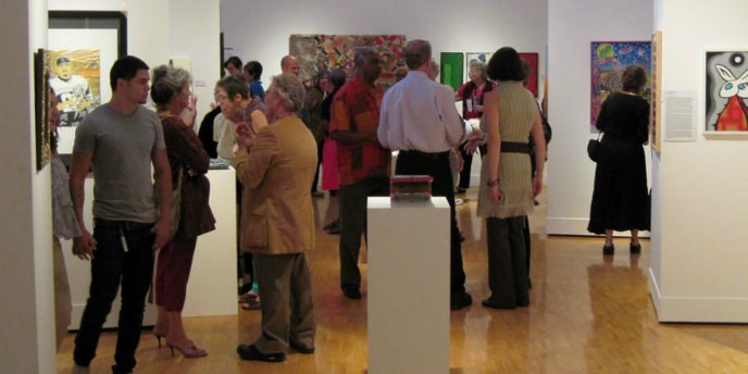 Small crowd of people looking at paintings on gallery walls Small crowd of people looking at paintings on gallery walls