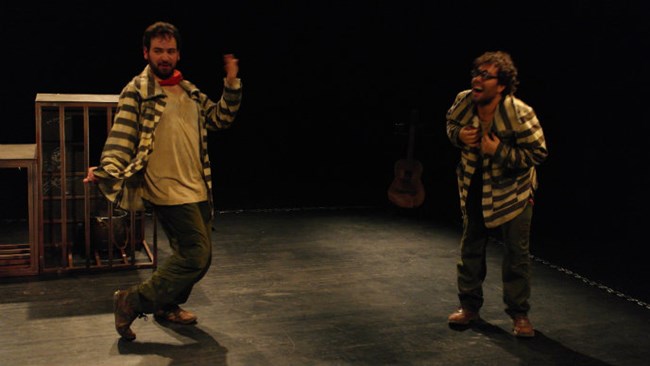Two male characters in a play on a stage, dressed as prisoners Two male characters in a play on a stage, dressed as prisoners