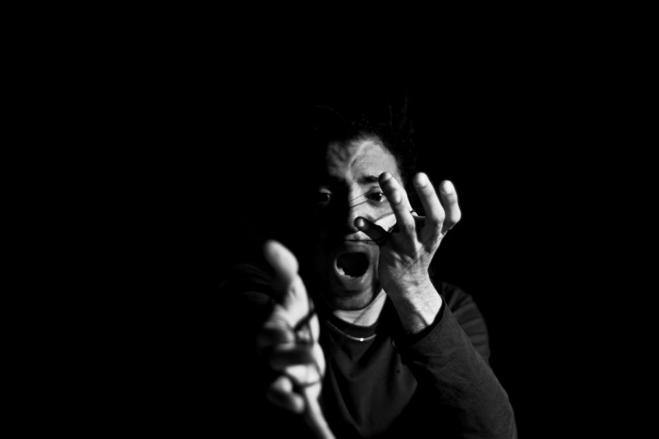 Jazz Vilá performs La Vida es Sueño actors hands and dramatic facial expression partially obscured against a dark background
