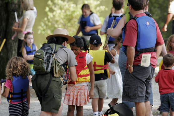 Park ranger helps a young boater buckle her PFD at a festival.