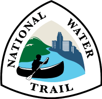 National Water Trail System official logo showing solo canoest paddleing down river with green hills to the left and urban skyline to the right.