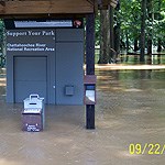 River water floods entrance fee station and wooded picnic area.