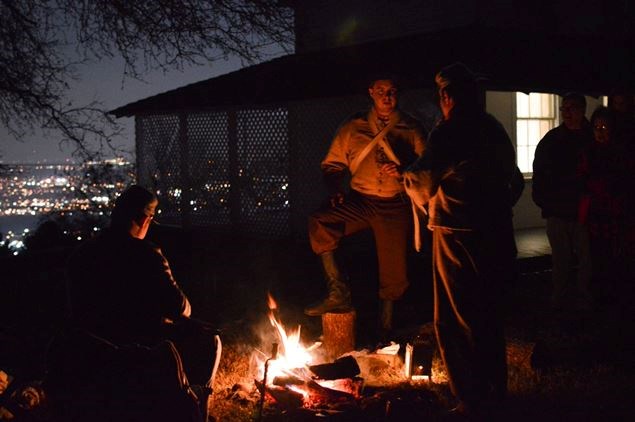 Living historians in Confederate uniforms talk to each other around a camp fire. ::Living historians around a camp fire