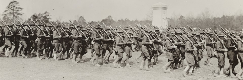 World War I soldiers marching in front of a monument