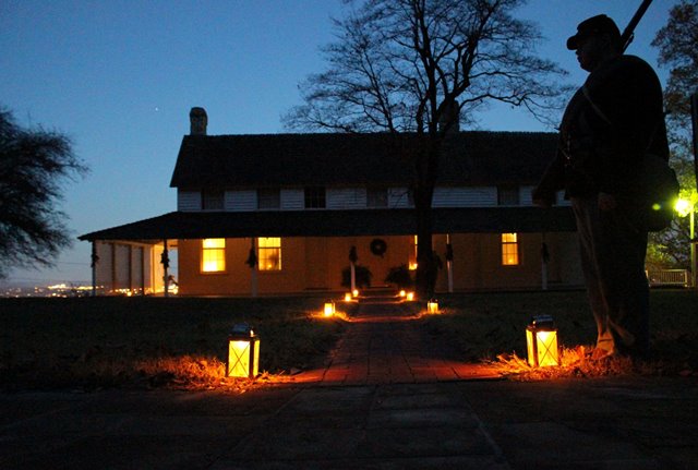 Cravens House illuminated by Christmas lights. A silhouetted Civil War soldier stands in the foreground.