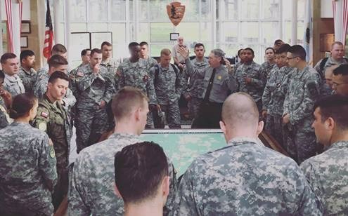 A park ranger addresses a group of soldiers around a large map.