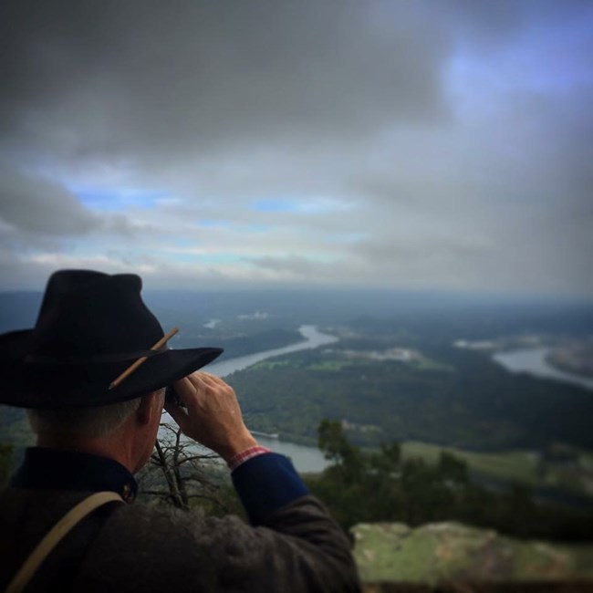 A Confederate officer looks through his binoculars toward Union artillery on Moccasin bend