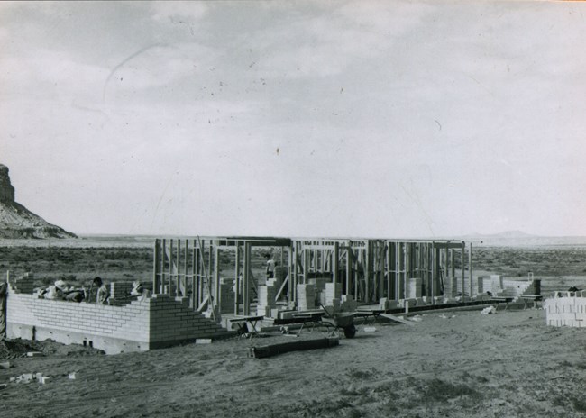 The wood and stone skeleton of a single story home and a vast open desert landscape in the background.