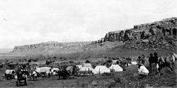 Tents, people, and carriages shown inside canyon walls.