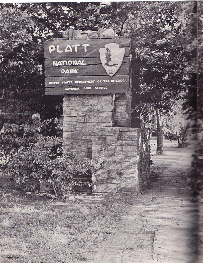 A wood sign for "Platt National Park" affixed to a stone pillar