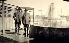 Two men standing next to an artesian well