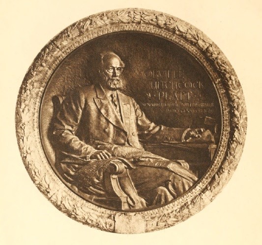 A round bronze plaque featuring an older man.