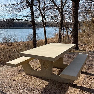 new cement picnic table with a lake in the background