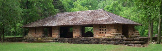 Stone pavilion structure in a cleared grassy field