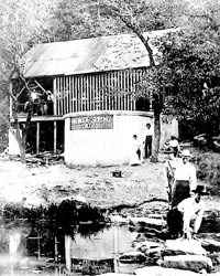 People in front of a rustic springhouse