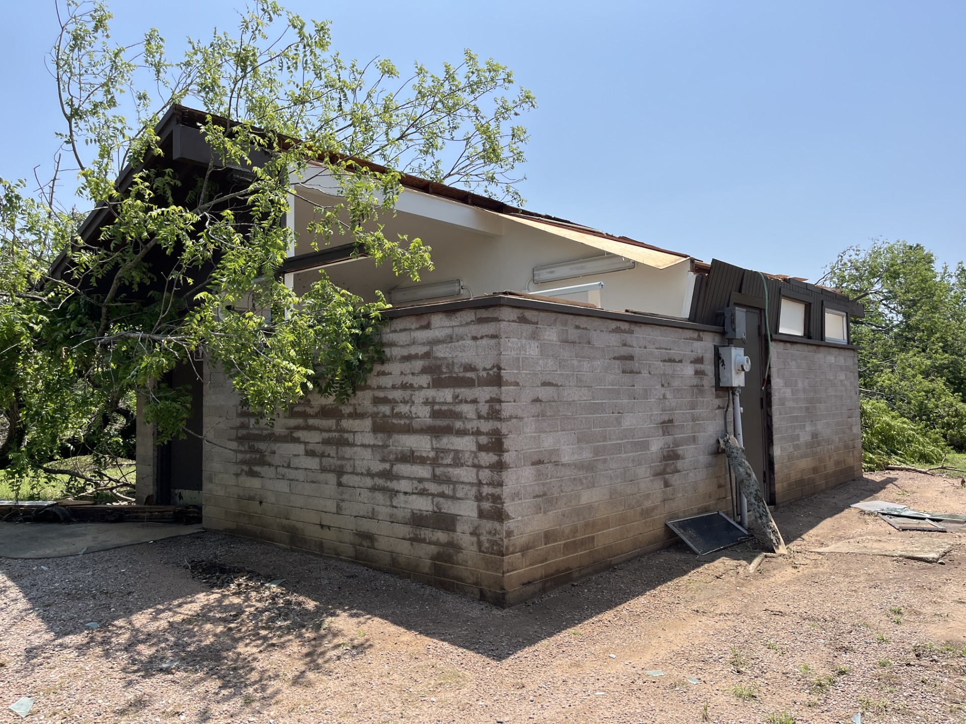 Black Sulphur Springs restroom 01May2024 A brick and wood restroom building with a good portion of the roof completely missing, a broken mirror on the ground, and tree limbs leaning up again the structure