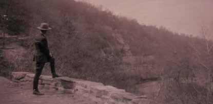 Old photo of a park ranger standing on a trail, looking into the distance
