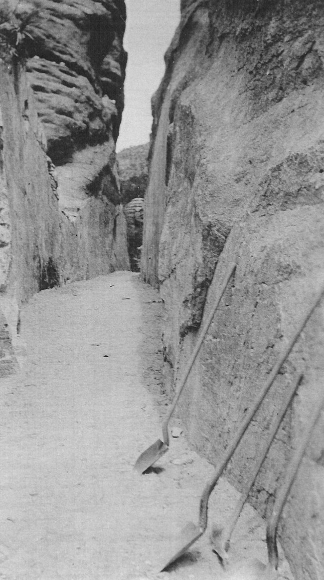Black and white photo of shovels in narrow rock canyon.