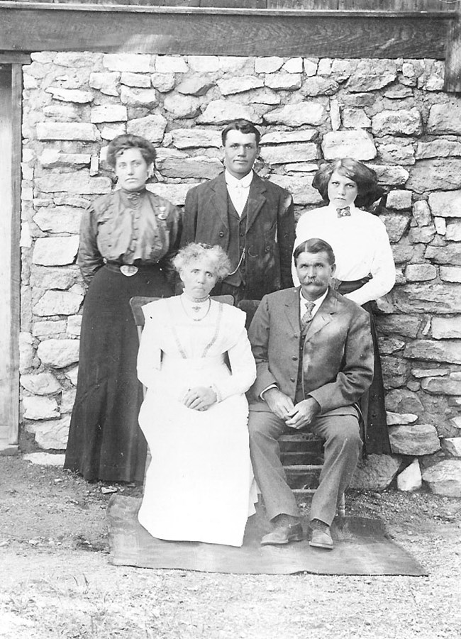 Family portrait of seated man and woman, and a woman, man, and another woman standing behind them.