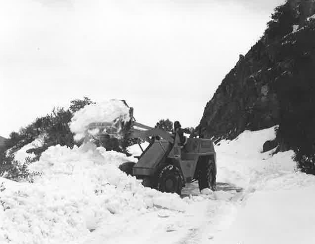 Black and white photo of snow removal on road using a backhoe. Black and white photo of snow removal on road using a backhoe.