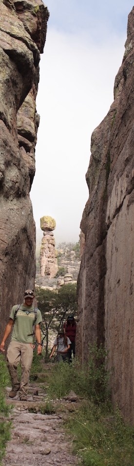 A hiker walks through steep rock canyon