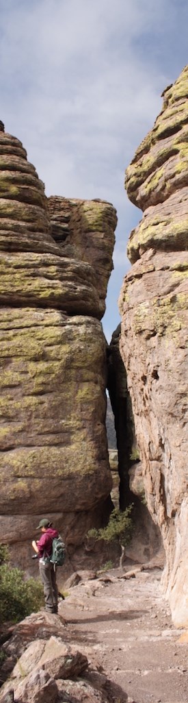 A hiker on the trail between steep rock formations