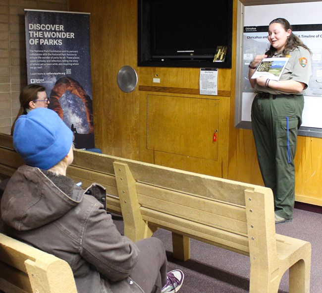 ranger stands in front of visitors with a picture of nature