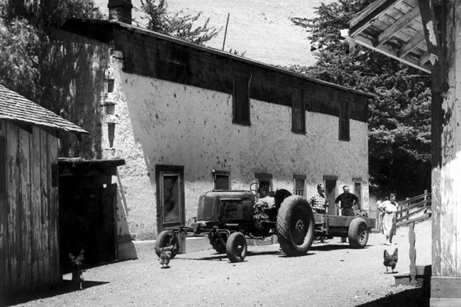 Ranch folks next to tractor and ranch house.