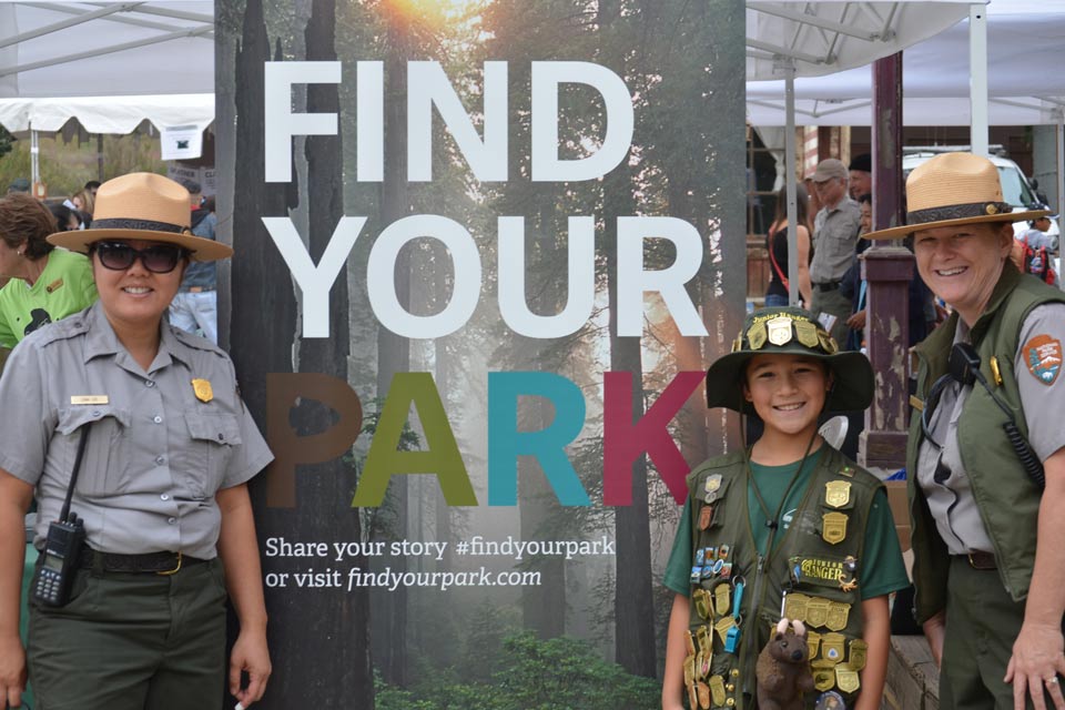 Junior ranger standing with two rangers.