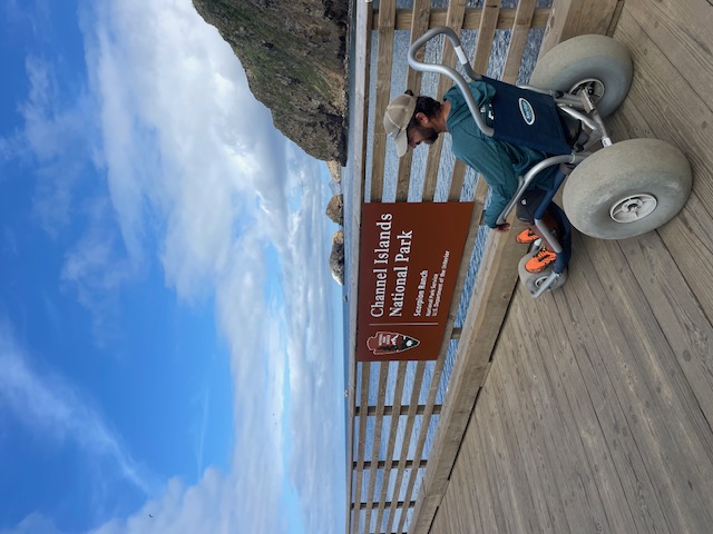 person in wheelchair on dock looking at ocean