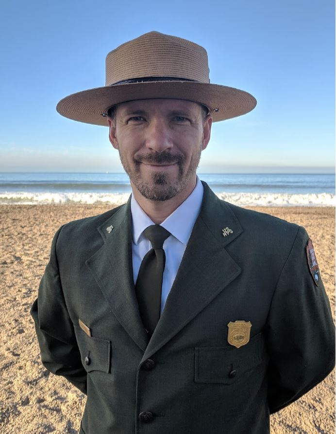 Man standing on beach with ranger hat.