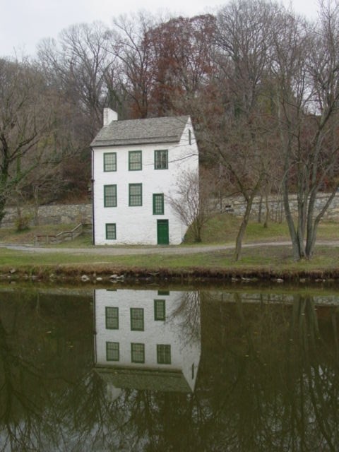 A white brick building reflected in the water below it