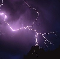 A lightning bolt branches across the night sky during a storm.