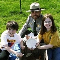 Ranger and two kids holding artifacts.