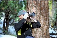 A person standing with a camera taking photos in the forest.