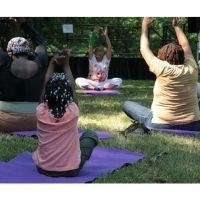 Park visitors enjoying yoga on the grass.