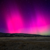 Aurora Borealis lights in sky over a landscape.