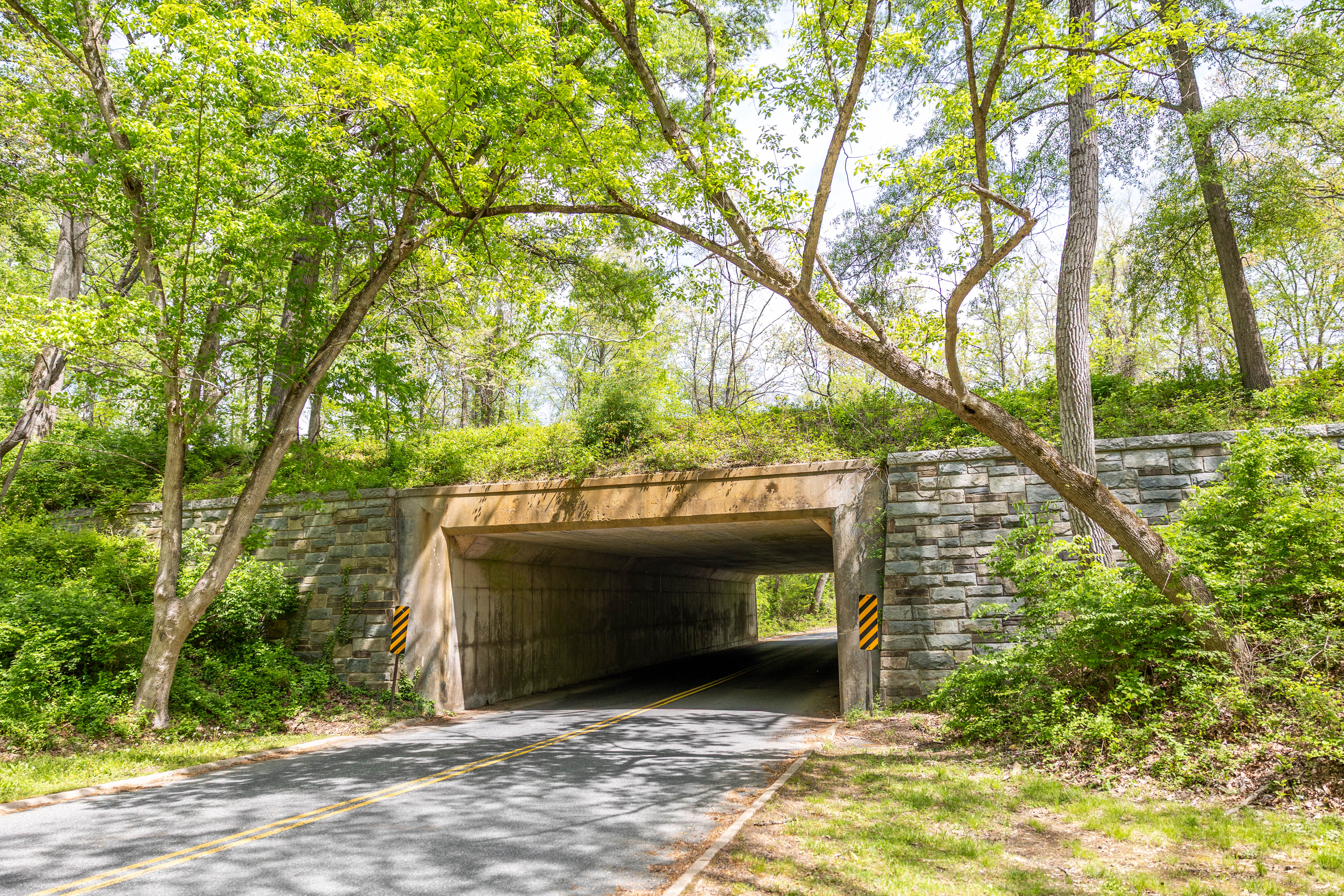 A stone and concrete box culvert with a paved 2-lane road running through it
