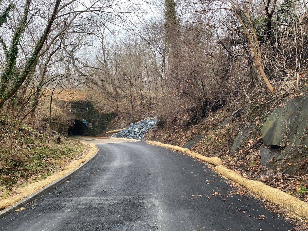 A newly paved road leads into a culvert road tunnel