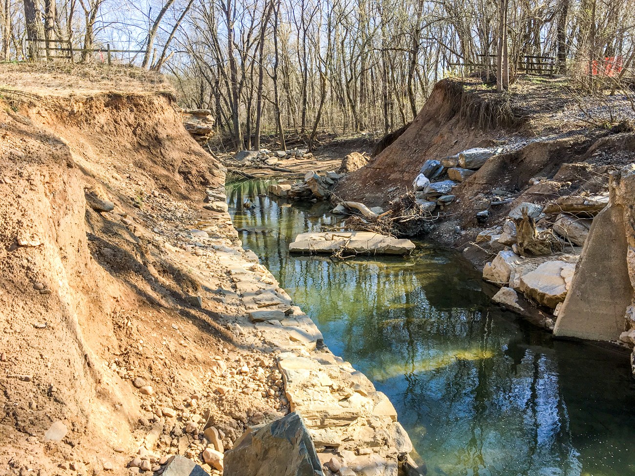 A stream runs through the remnants of a washed out masonry culvert