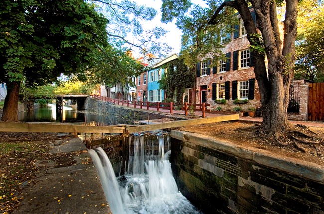 canal with water flowing through wooden structures called gates.  Canal is surrounded by brick buildings