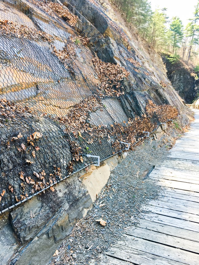 A large rock wall with mesh over it near the Paw Paw Tunnel