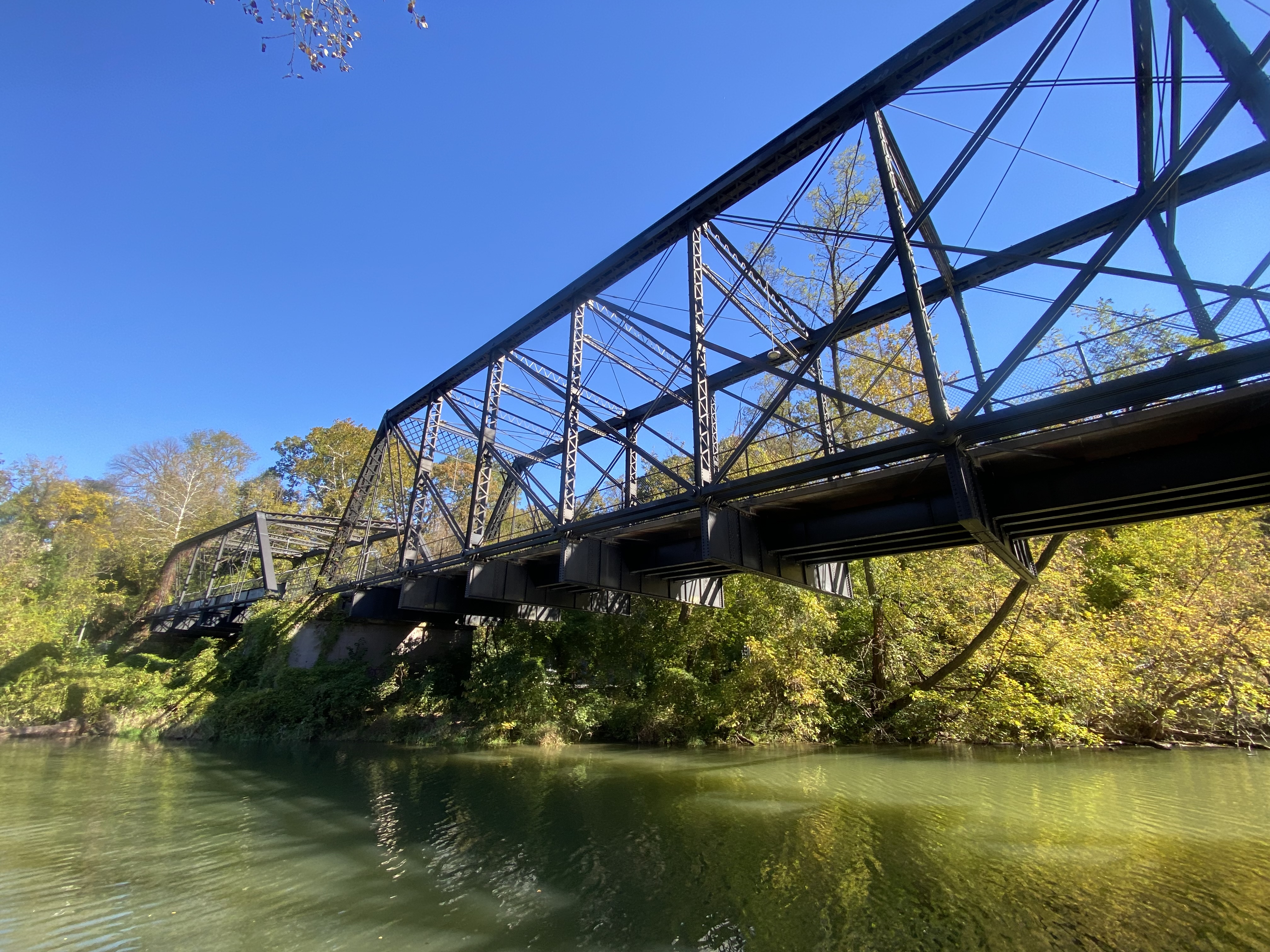 A metal truss bridge stretches over a body of water