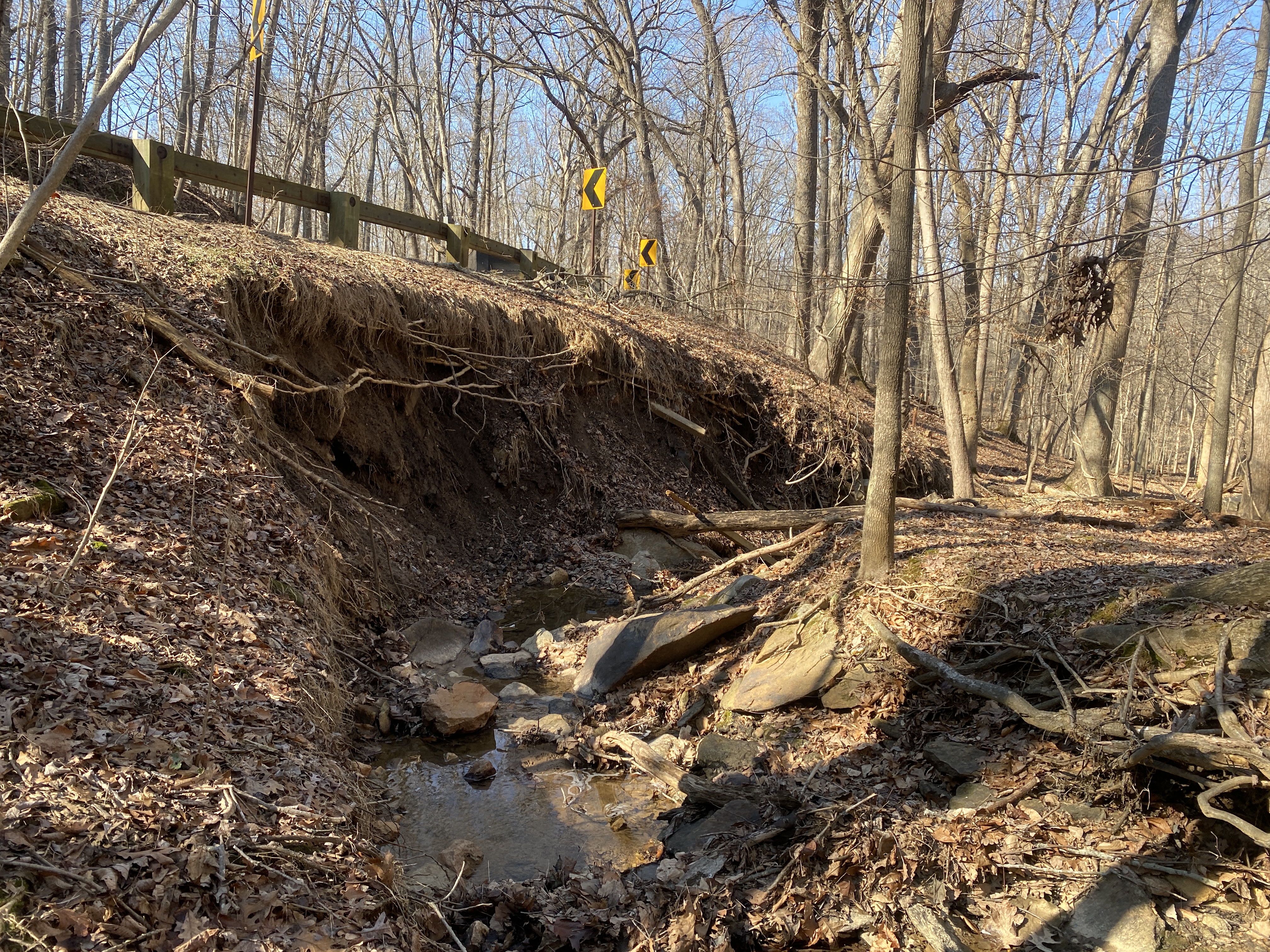 A stream causes erosion along a roadway