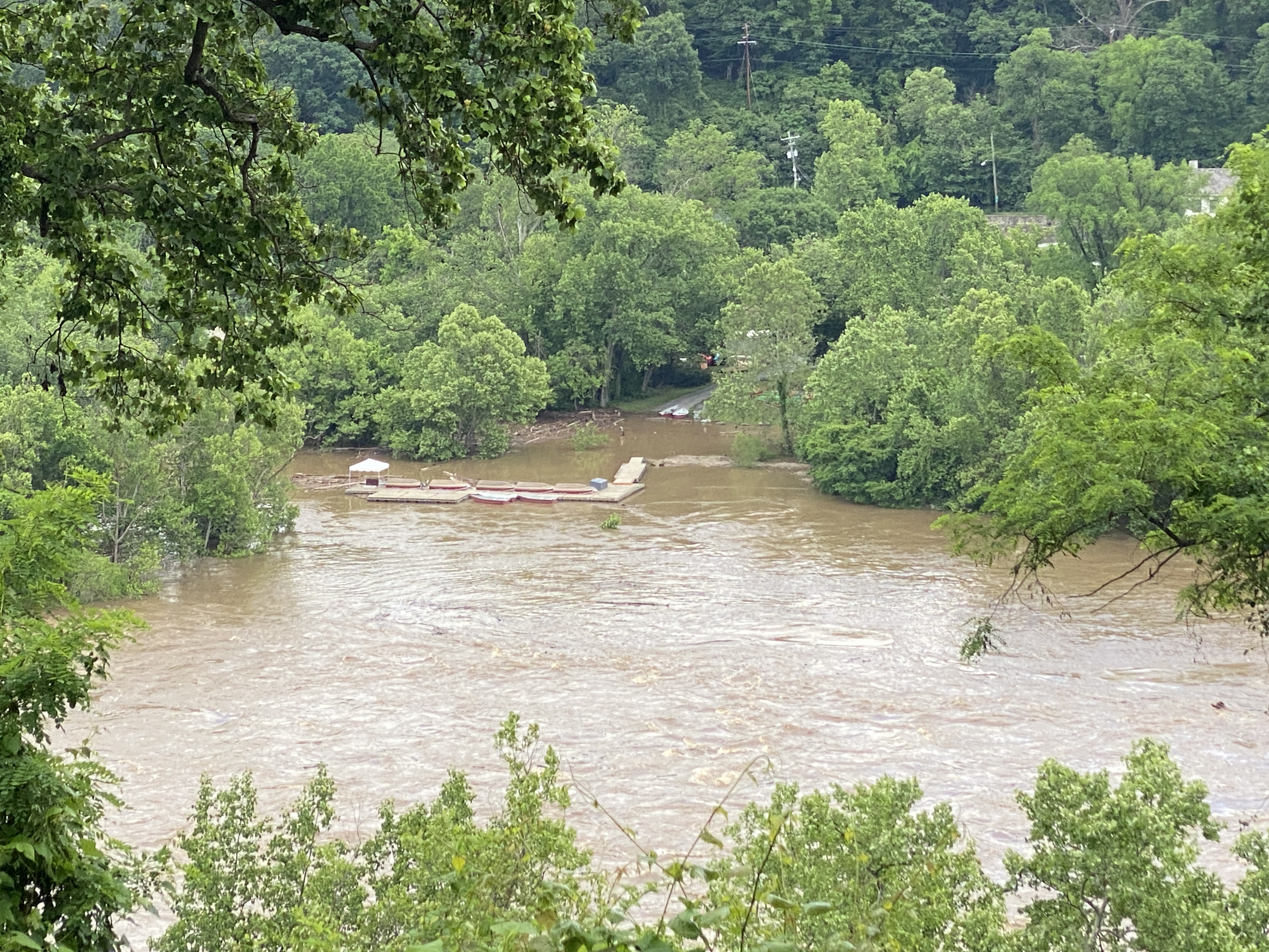 A muddied body of water during a flood event with a wooden floating boat dock in the middle