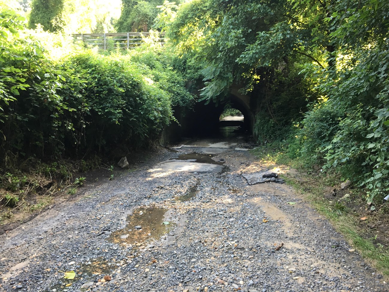 A gravel road with erosion on its surface runs through a tunnel