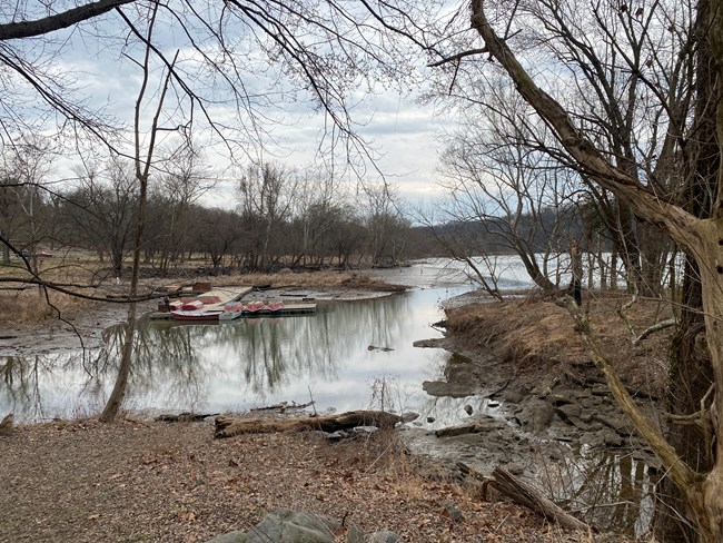 A silted in body of water with a wooden boat dock in the middle