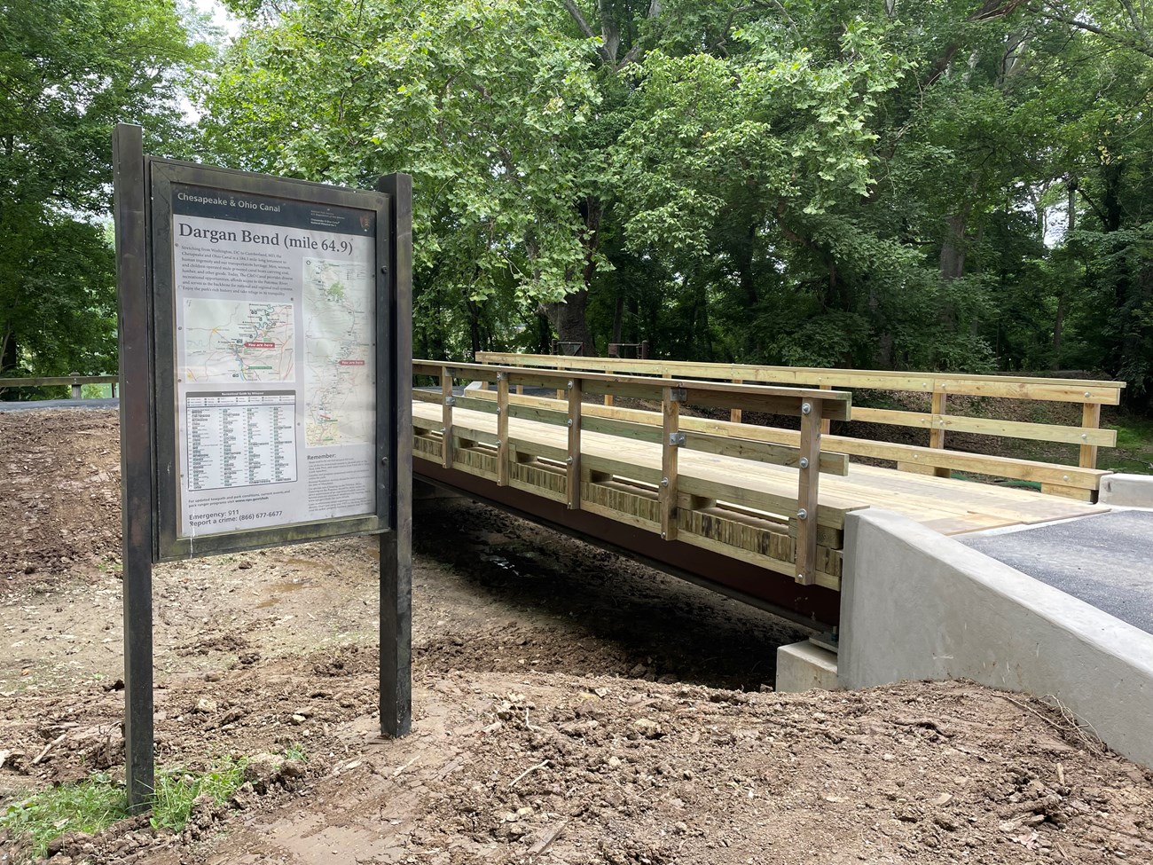 A wooden vehicle bridge crosses over a dry canal prism
